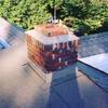 A residential flat roof — chimney flashings spliced into masonry and roof.